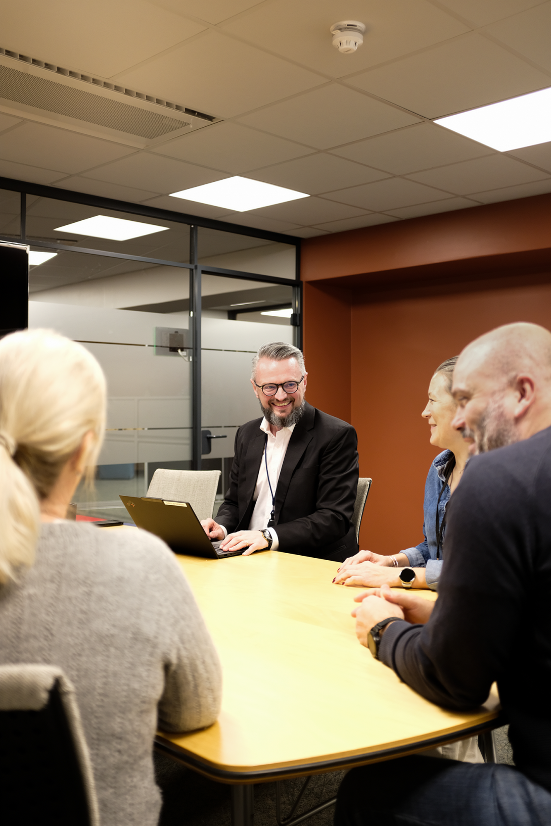 4 medarbeidere sitter rundt et bord. Fokus er på en blid adm.dir, Sven-Olav Svendsen